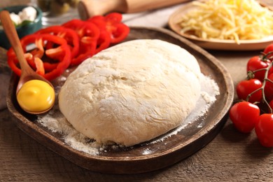 Photo of Pizza dough and products on wooden table, closeup