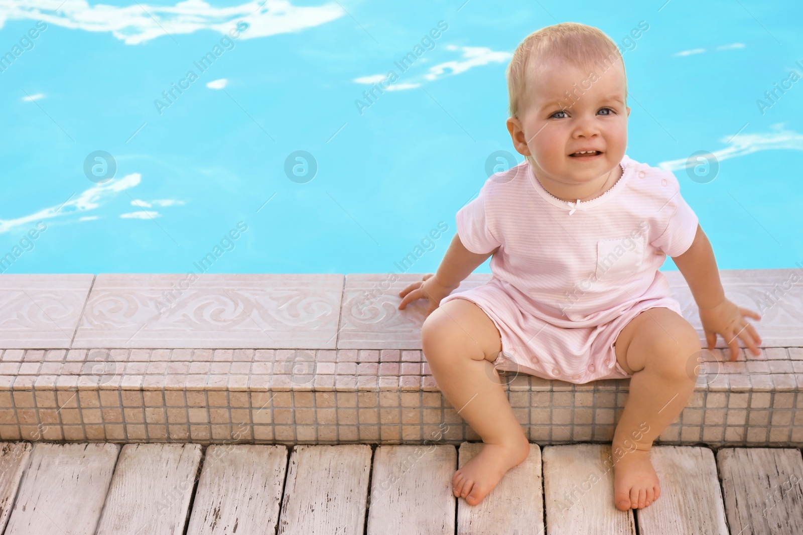 Photo of Little baby sitting near outdoor swimming pool. Dangerous situation