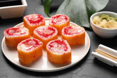 Delicious sushi rolls with salmon and tobiko on grey textured table, closeup