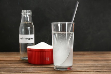 Glass with water and baking soda on wooden table