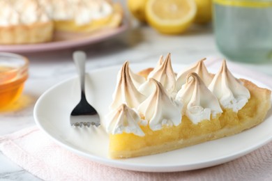 Photo of Piece of delicious lemon meringue pie served on white marble table, closeup