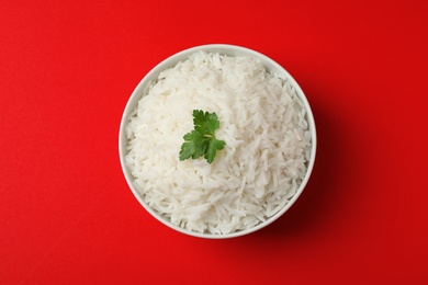 Photo of Bowl of tasty cooked rice with parsley on color background, top view