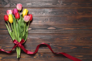 Photo of Beautiful colorful tulips on wooden table, top view. Space for text