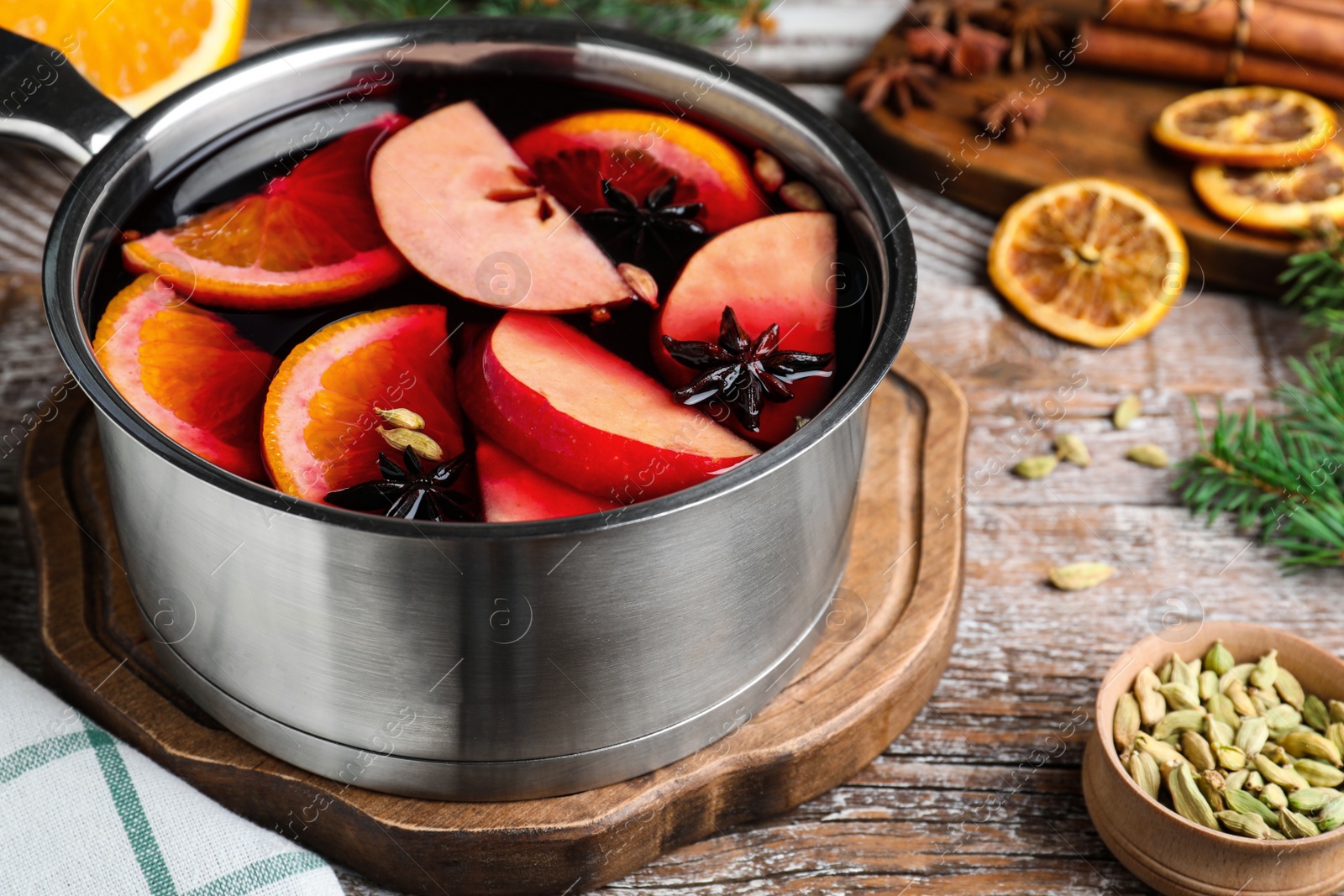 Photo of Delicious mulled wine and ingredients on wooden table, closeup