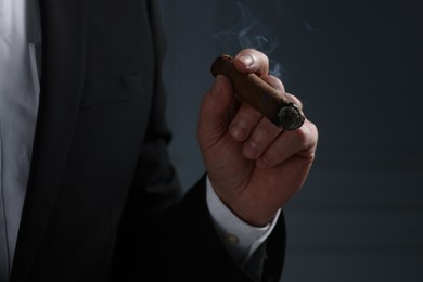 Photo of Man smoking cigar on dark grey background, closeup