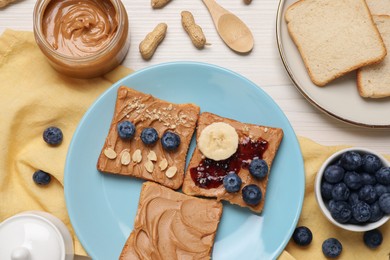 Different tasty toasts with nut butter and products on white wooden table, flat lay