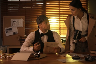 Photo of Old fashioned detective and his colleague working in office