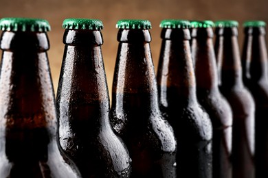 Many bottles of beer on light brown background, closeup
