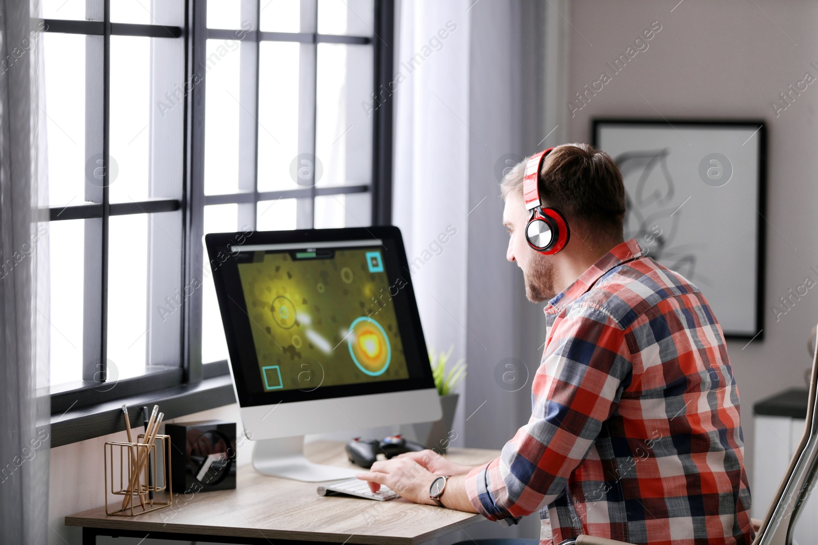 Photo of Young man playing video game at home