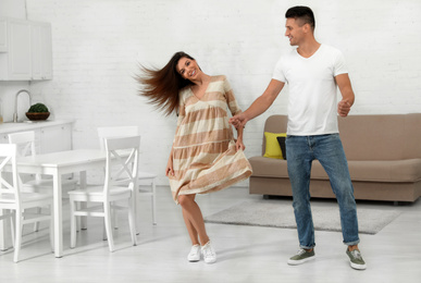 Happy couple dancing in kitchen at home