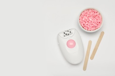 Photo of Modern epilator, sticks and wax on white background, flat lay. Space for text