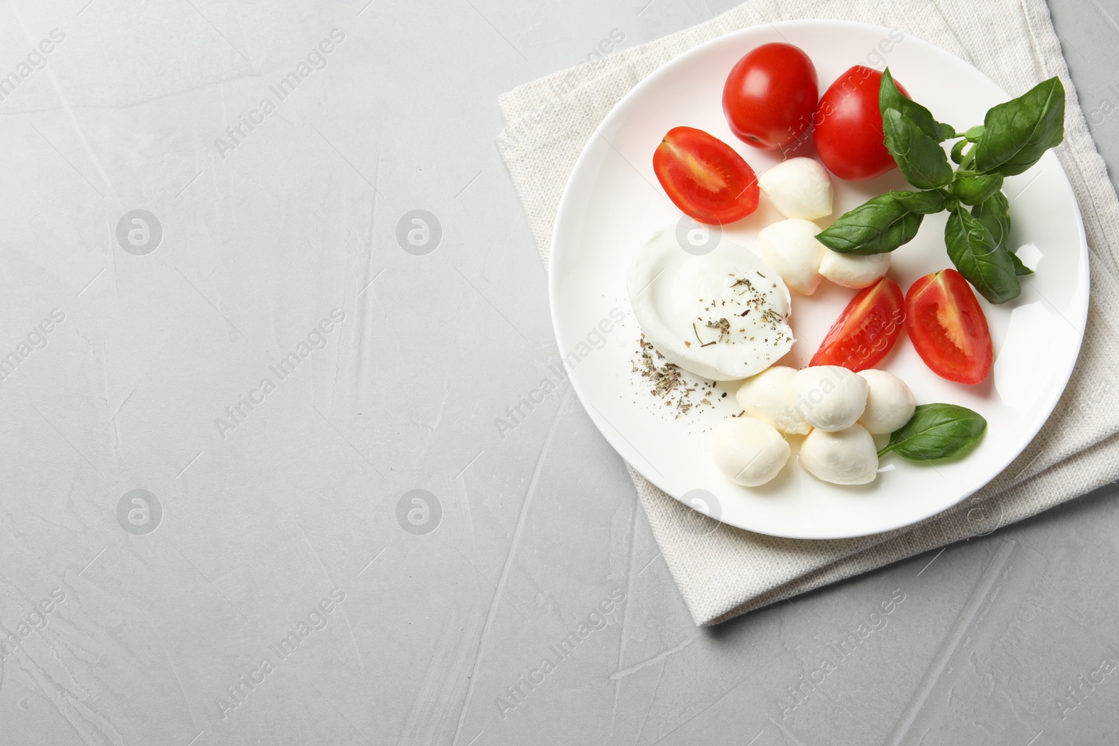 Photo of Delicious mozzarella with tomatoes and basil leaves on light gray table, top view. Space for text