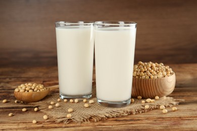 Photo of Glasses with fresh soy milk and grains on wooden table