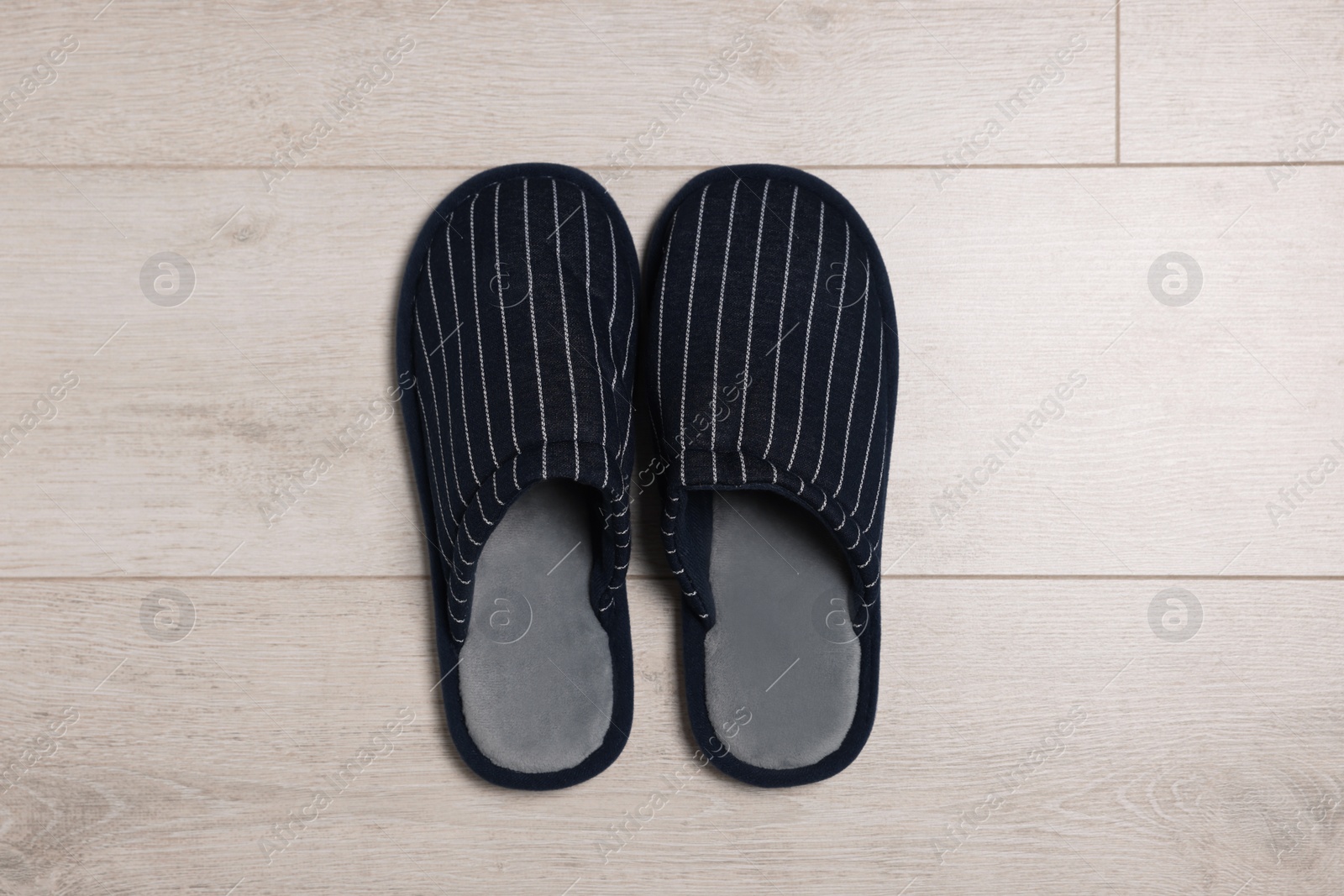 Photo of Pair of stylish slippers on white wooden floor, top view