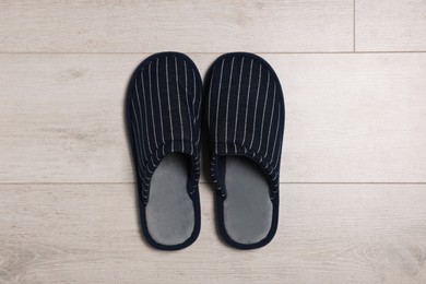 Photo of Pair of stylish slippers on white wooden floor, top view