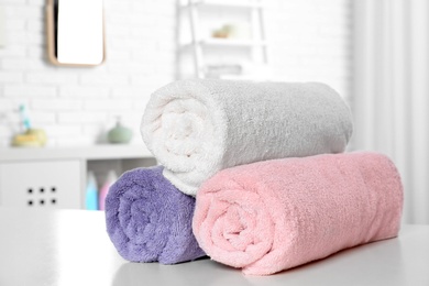 Photo of Rolled fresh towels on table in bathroom
