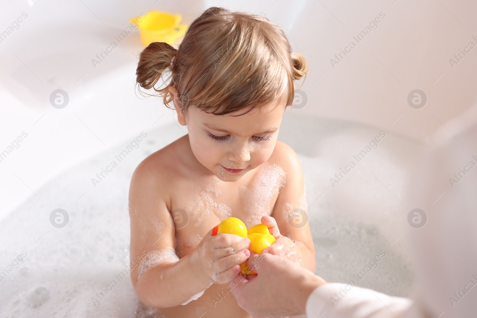 Photo of Mother playing with her little daughter in bath tub, closeup