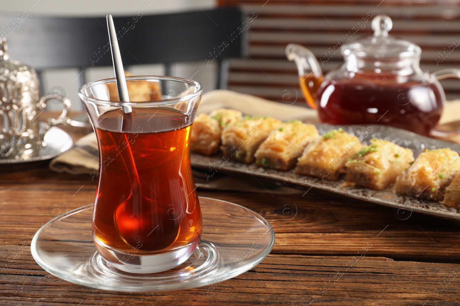 Photo of Traditional Turkish tea in glass and fresh baklava on wooden table