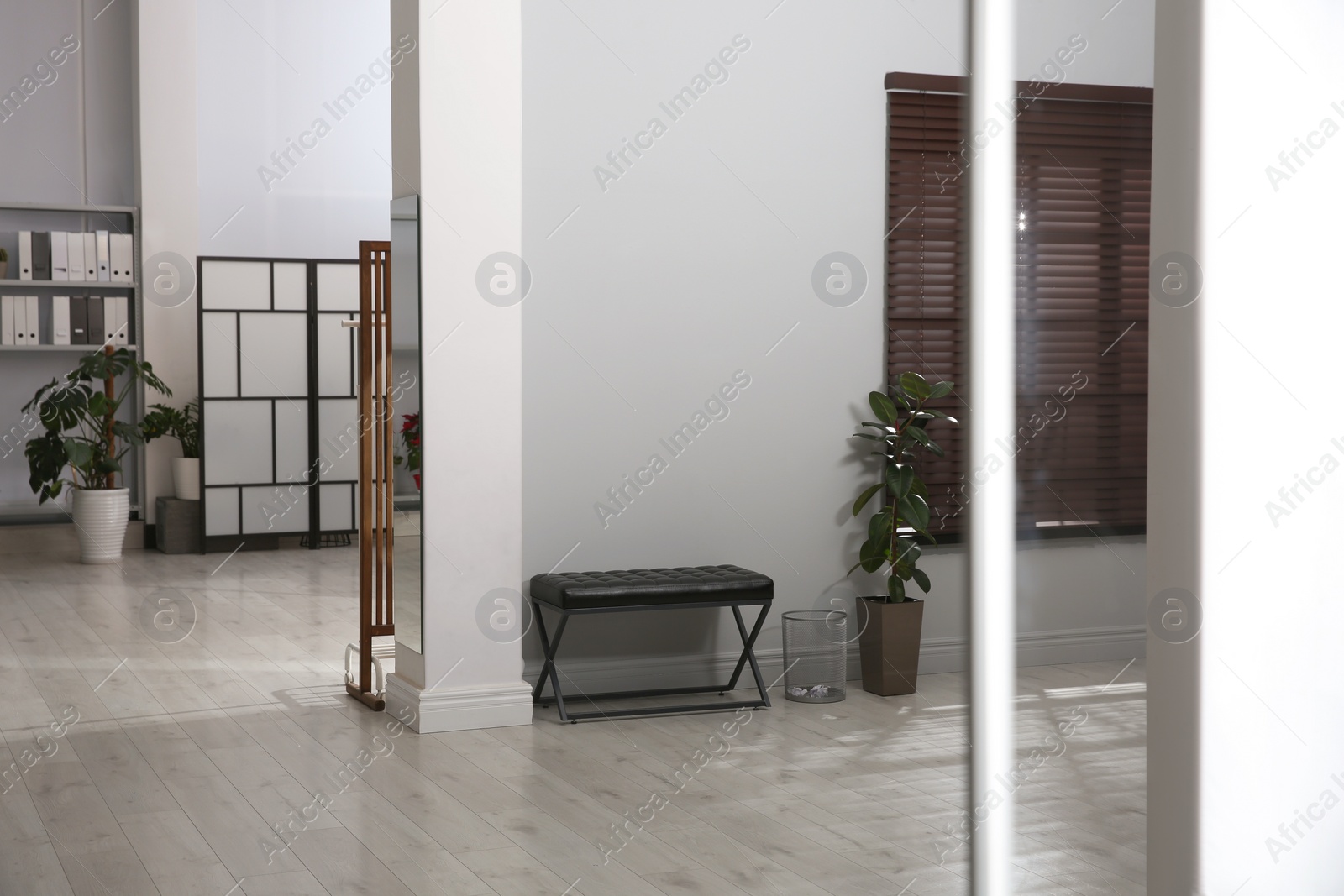 Photo of Empty long office corridor with bench and green potted plants