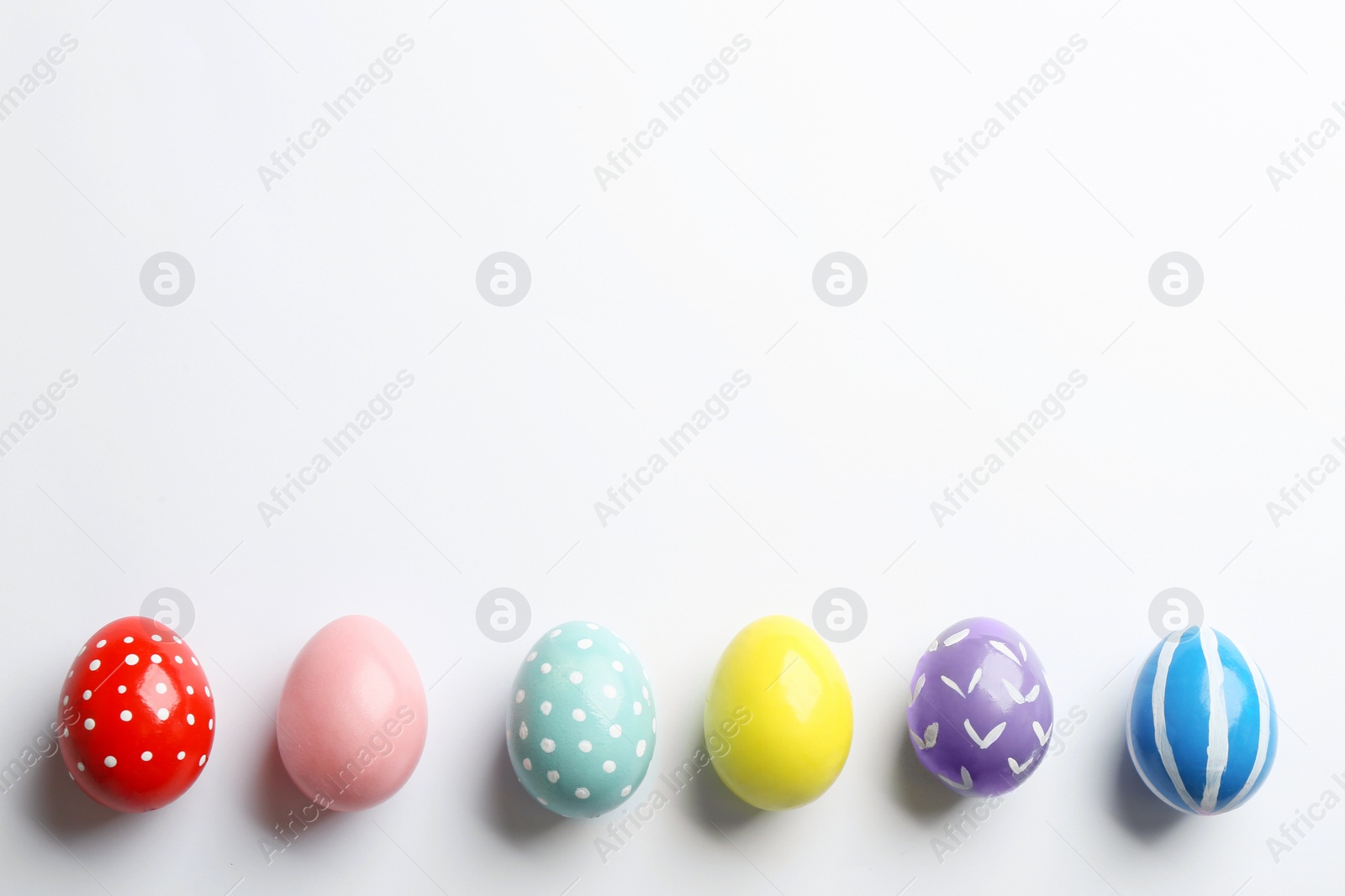 Photo of Composition of painted Easter eggs on white background, top view