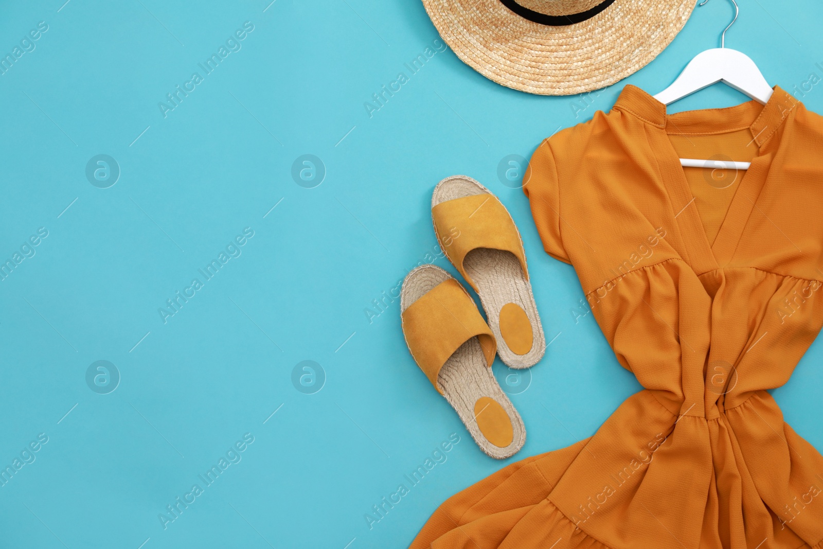 Photo of Dress, straw hat and shoes on light blue background, flat lay with space for text. Clothes rent concept