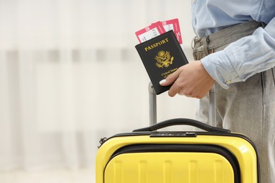 Woman with suitcase, passport and tickets on blurred background, closeup. Space for text