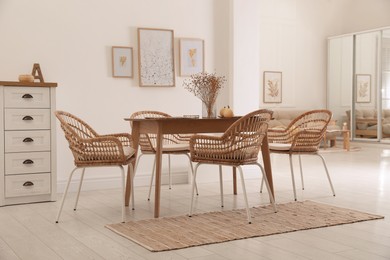 Photo of Dining room interior with wooden table and wicker chairs