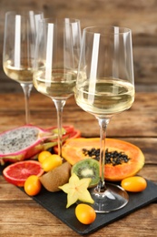 Delicious exotic fruits and wine on wooden table