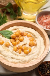 Bowl with delicious hummus and chickpeas on table, closeup