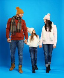 Happy family in warm clothes on blue background. Winter vacation