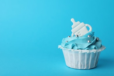 Baby shower cupcake with topper on light blue background, space for text