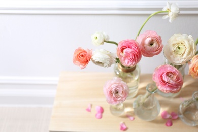 Photo of Beautiful ranunculus flowers on table near wall, above view. Space for text