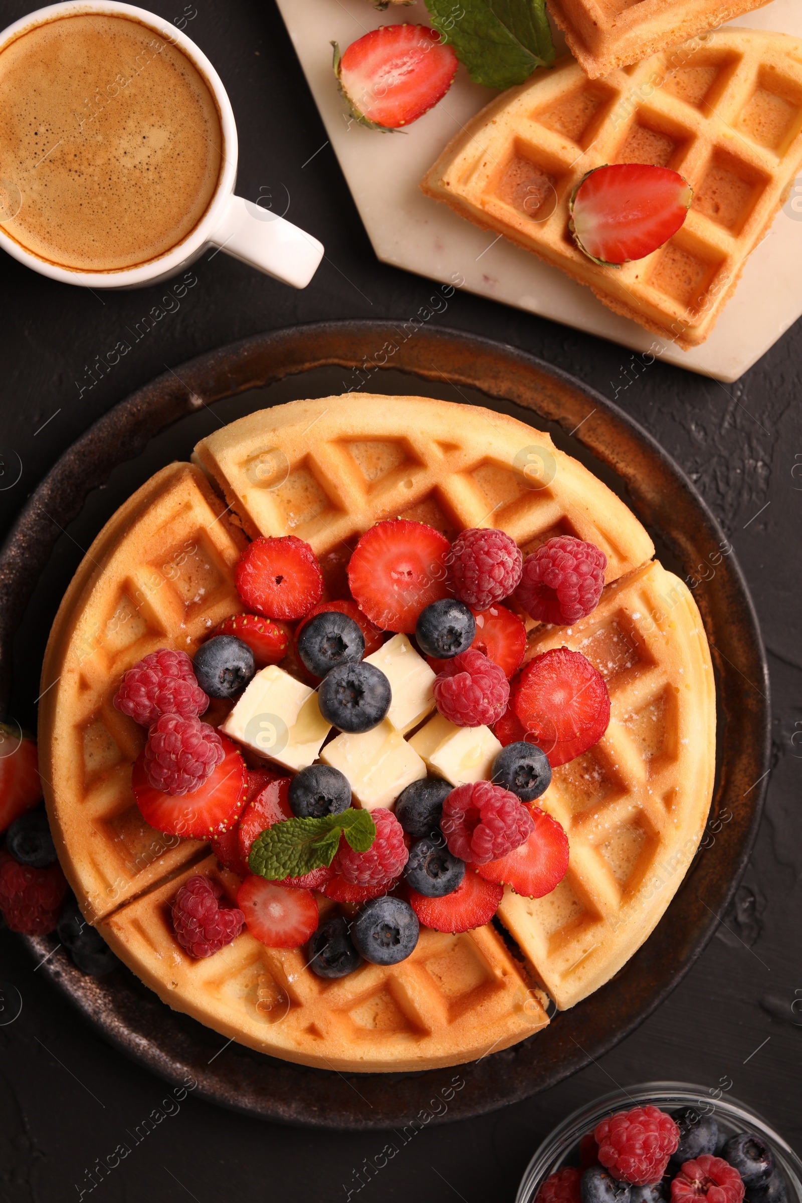 Photo of Tasty Belgian waffles with fresh berries, cheese and cup of coffee on black table, flat lay