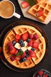 Tasty Belgian waffles with fresh berries, cheese and cup of coffee on black table, flat lay