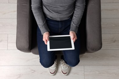Photo of Man working with tablet in armchair, top view