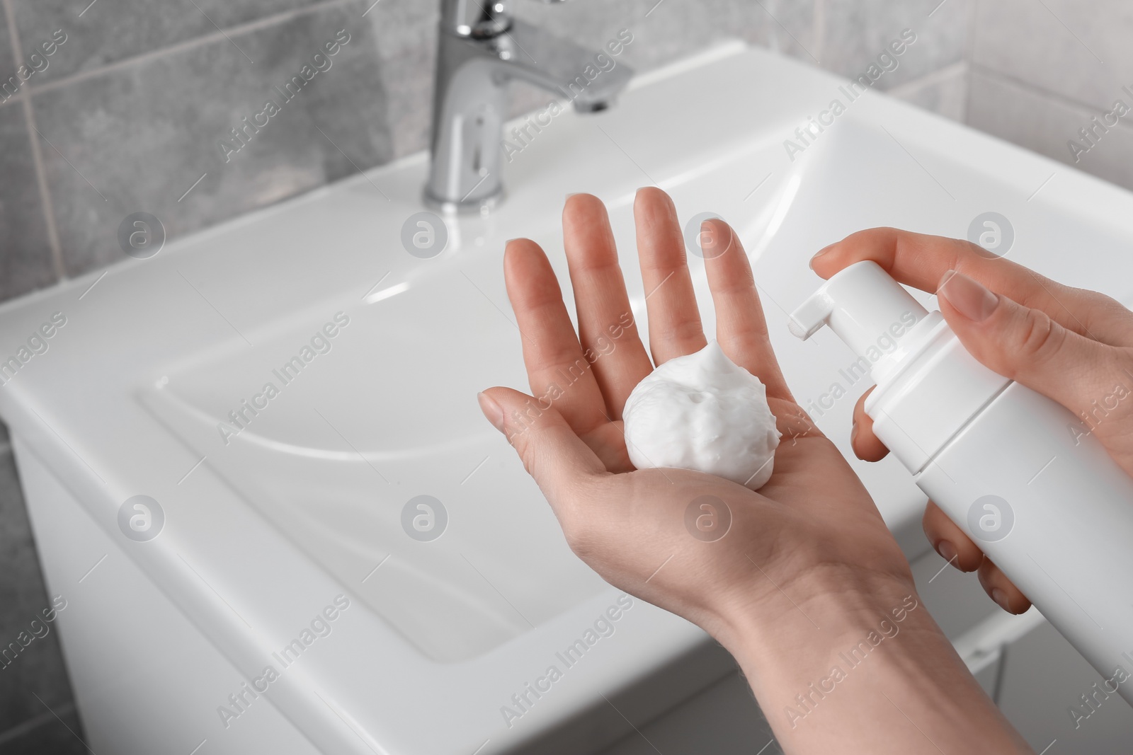 Photo of Woman washing hands with cleansing foam near sink in bathroom, closeup. Space for text