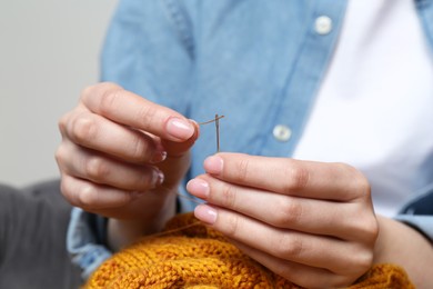 Photo of Woman inserting thread through eye of needle, closeup