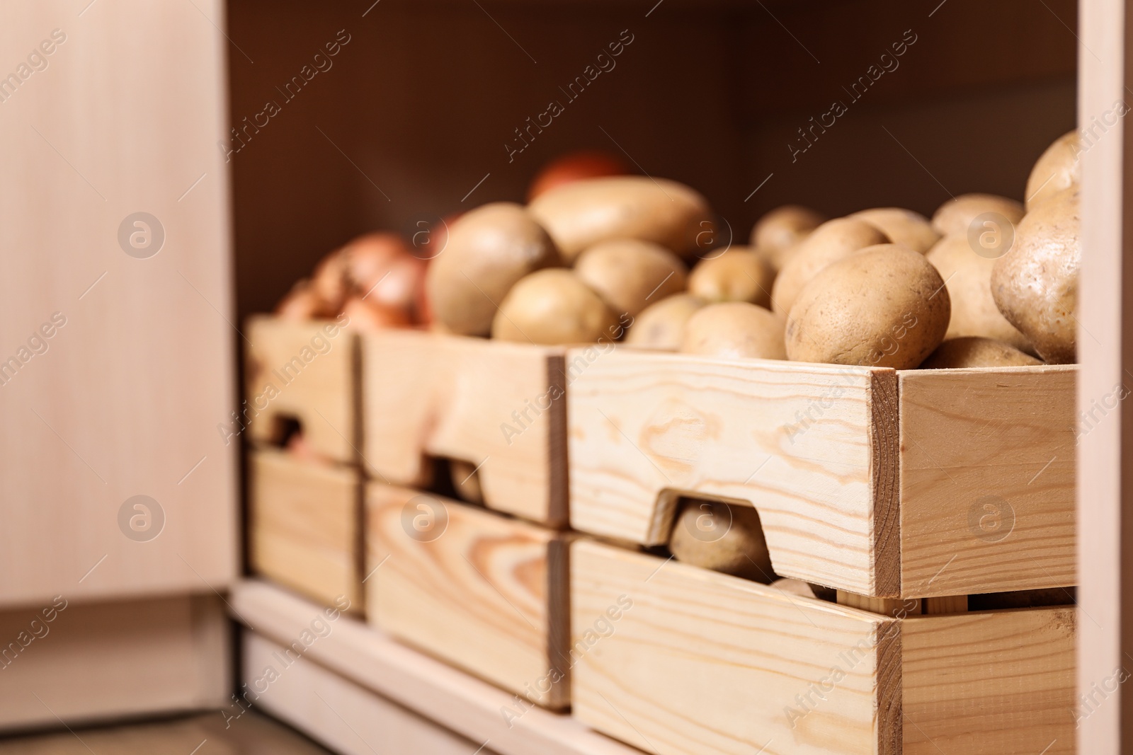 Photo of Crates with potatoes on shelf, closeup. Orderly storage