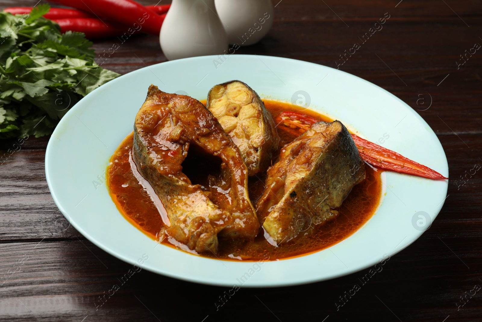 Photo of Tasty fish curry on wooden table, closeup. Indian cuisine