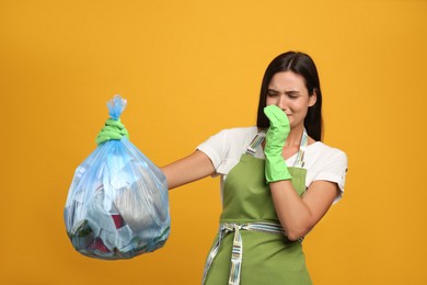 Photo of Woman holding full garbage bag on yellow background