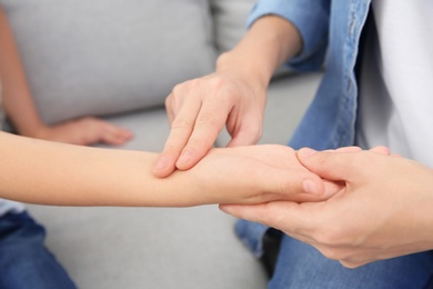 Photo of Young woman checking little girl's pulse, closeup