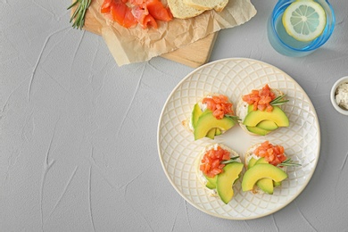 Photo of Plate of tasty sandwiches with fresh sliced salmon fillet and avocado on table, top view