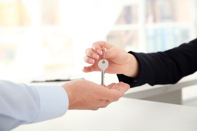 Young man receiving key from receptionist in hotel, closeup