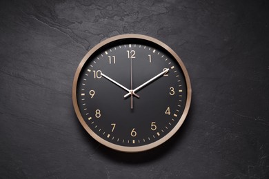 Stylish round clock on black table, top view. Interior element