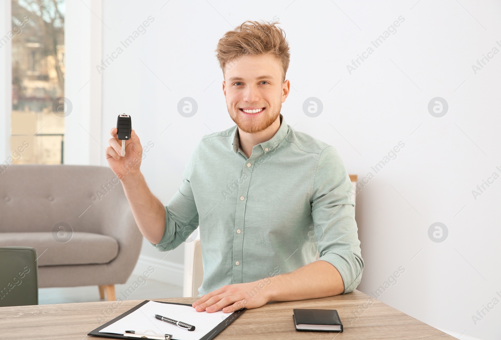 Photo of Young man with new car key in dealership