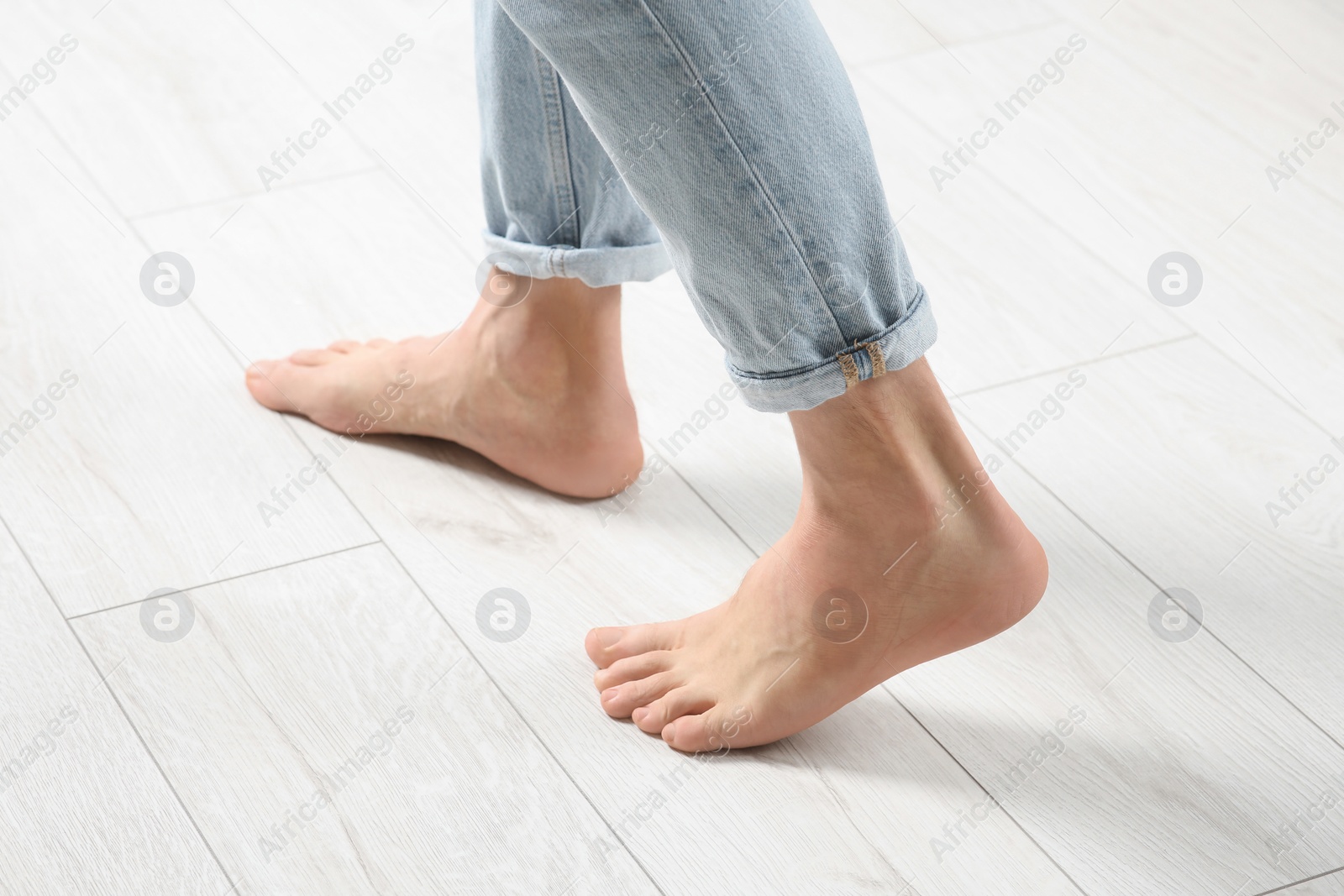 Photo of Barefoot woman walking on white parquet, closeup. Heated floor