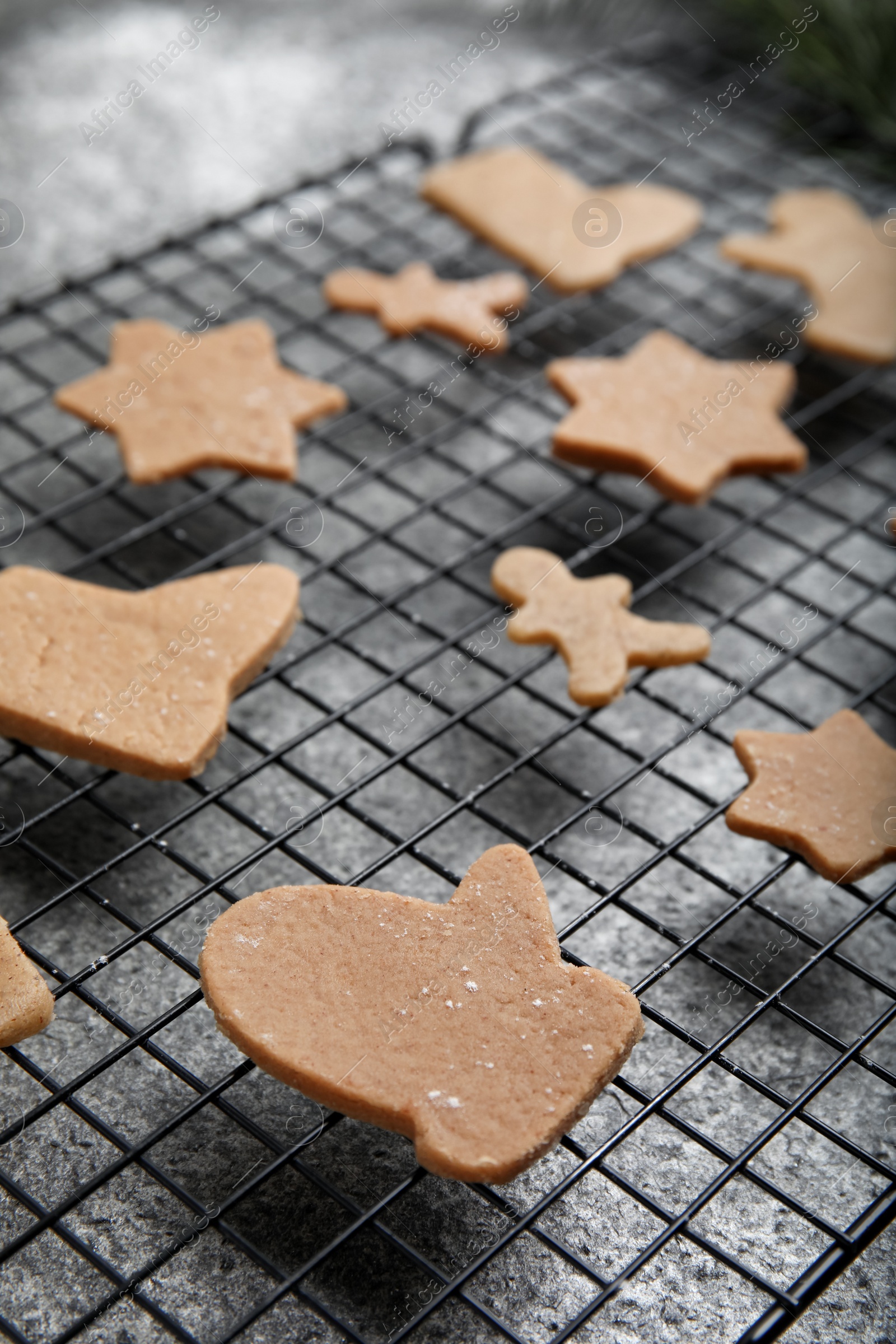 Photo of Homemade Christmas cookies. Baking rack with raw gingerbread biscuits on grey table, closeup
