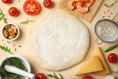 Photo of Flat lay composition with dough and fresh ingredients for seafood pizza on beige background