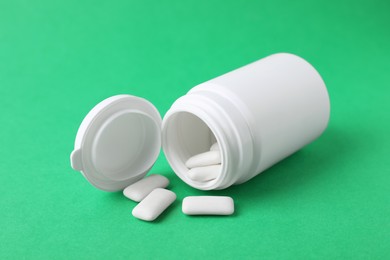 Photo of Jar with chewing gums on green background, closeup