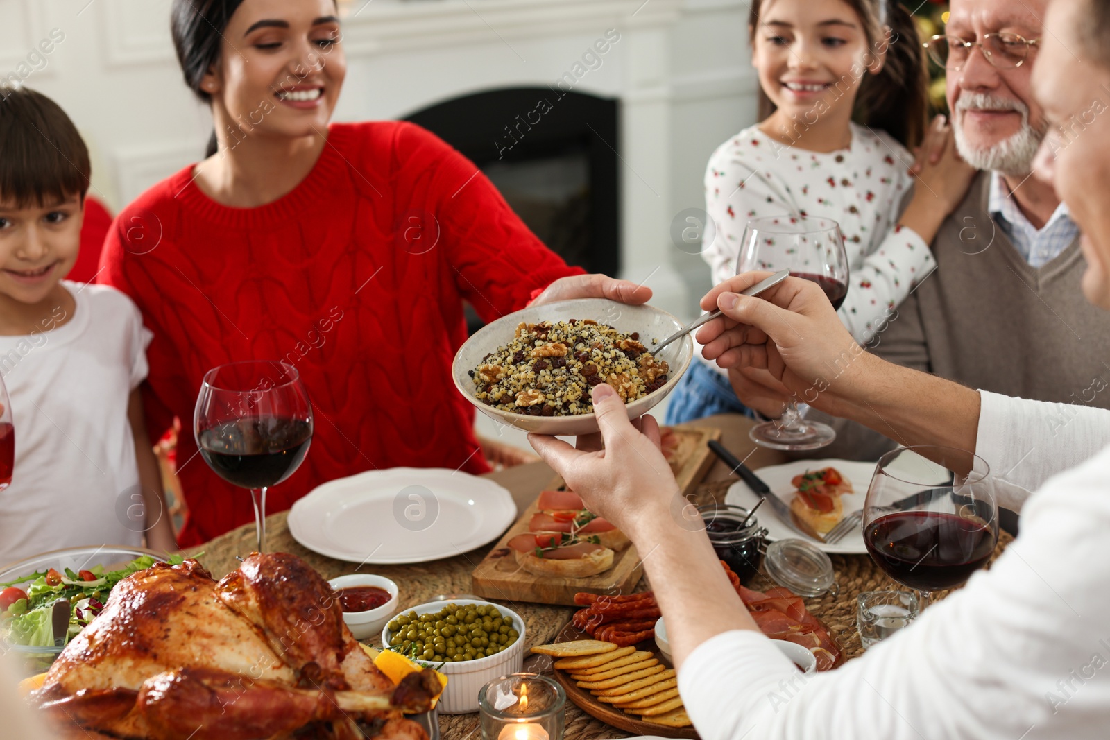 Photo of Man giving bowl of traditional Christmas kutia to woman at festive dinner, focus on hands. Slavic dish